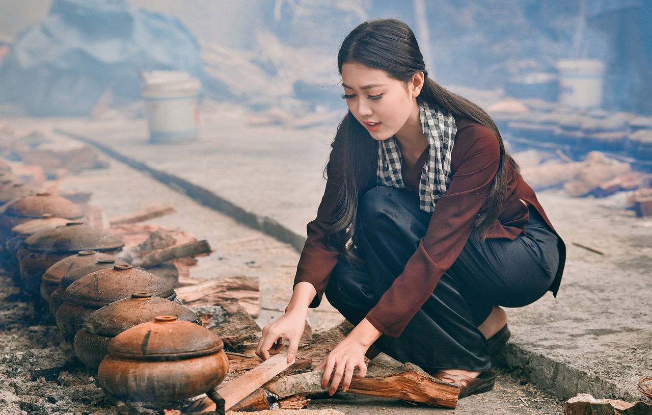 A woman cooking on stoneware potteries on wooden stoves Asian woman cooking on stoneware potteries in a traditinal way using wooden stove method